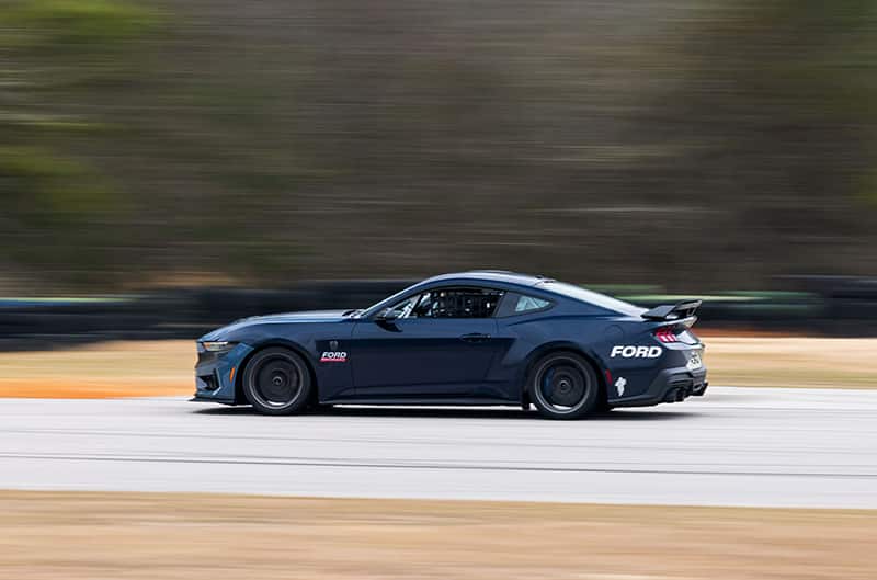 Dark Horse R Mustang driving to the left at speed on track